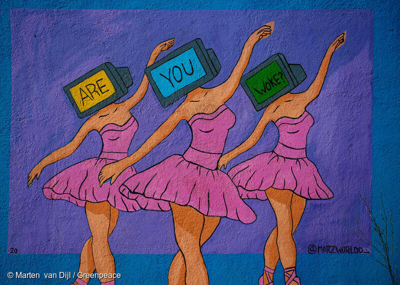 A mural with a purple and blue background depicting 3 ballerinas wearing pink dresses. The dancers have TVs as heads which each contain one word, spelling out "ARE YOU WOKE?" together.